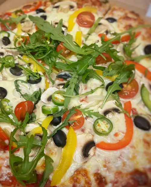 Vegetable pizza with fresh rocket leaves